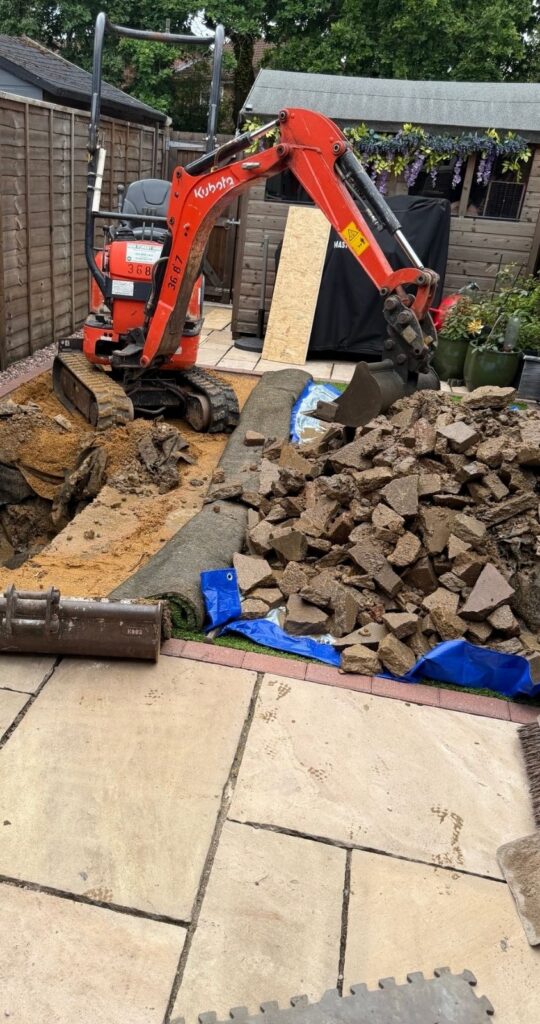 Mini excavator undertaking drainage repair and excavation work at a residential property