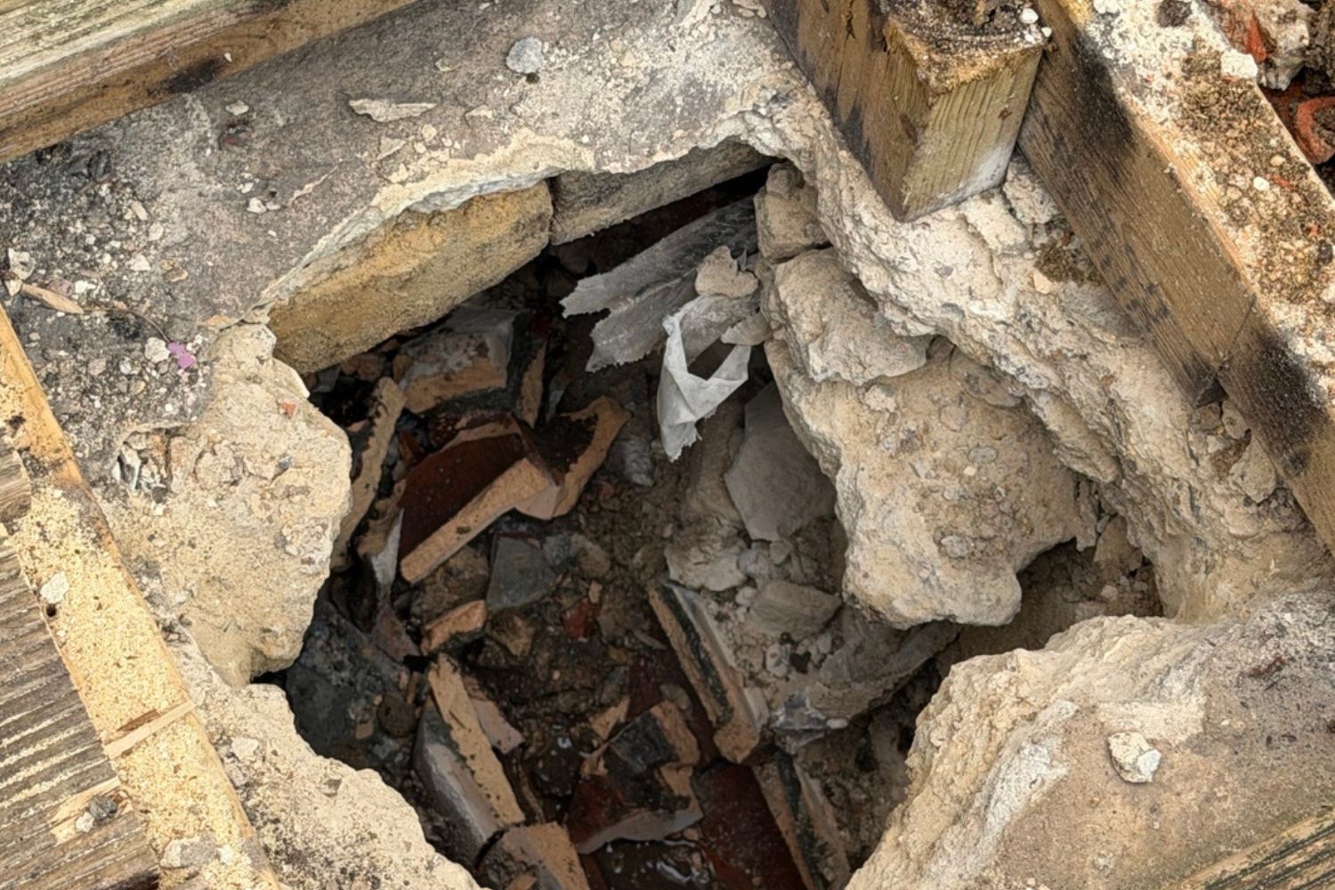 Excavated drainage area showing damaged pipework and collapsed surrounding ground.